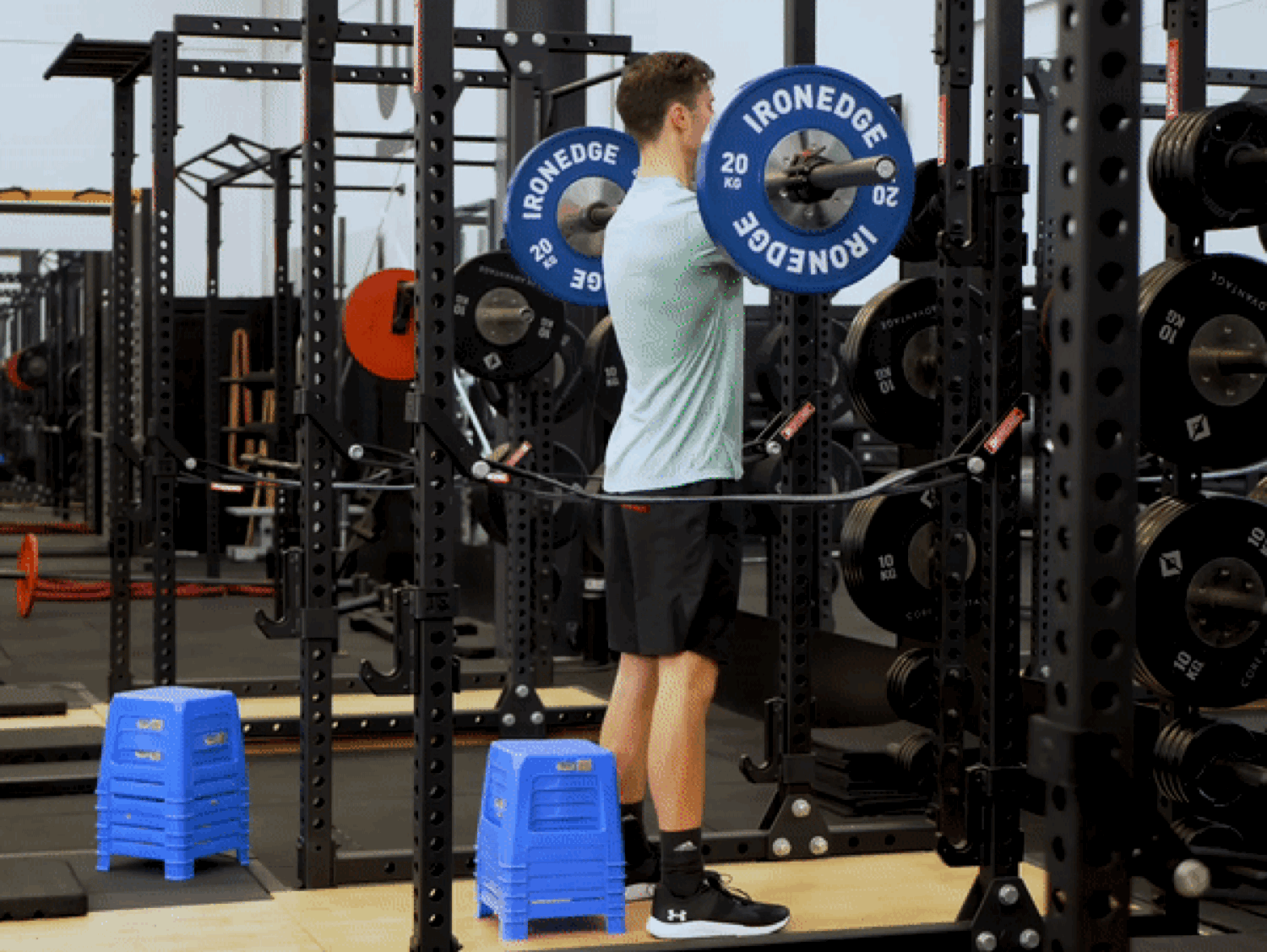 Athlete performing a barbell back squat in a power rack